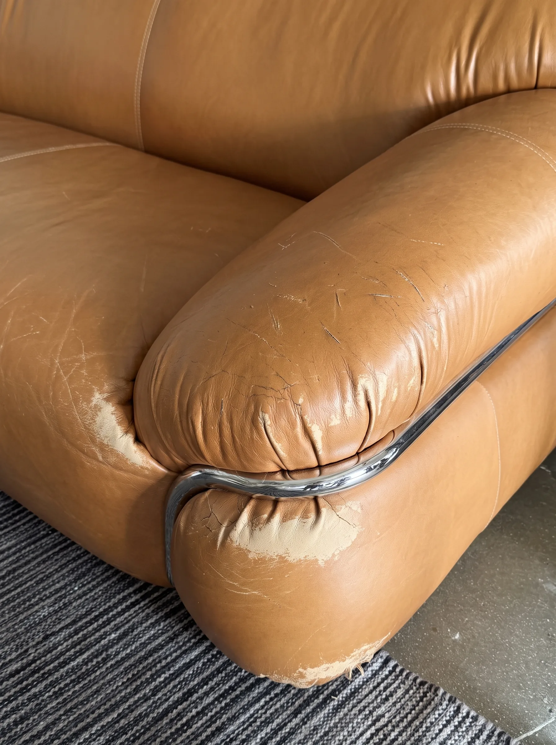 Scuffed camel leather sofa arm before repair
